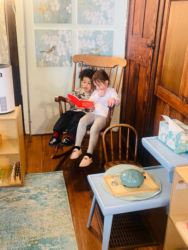 Small group of children reading together in cozy Montessori classroom corner, fostering literacy and community bonds